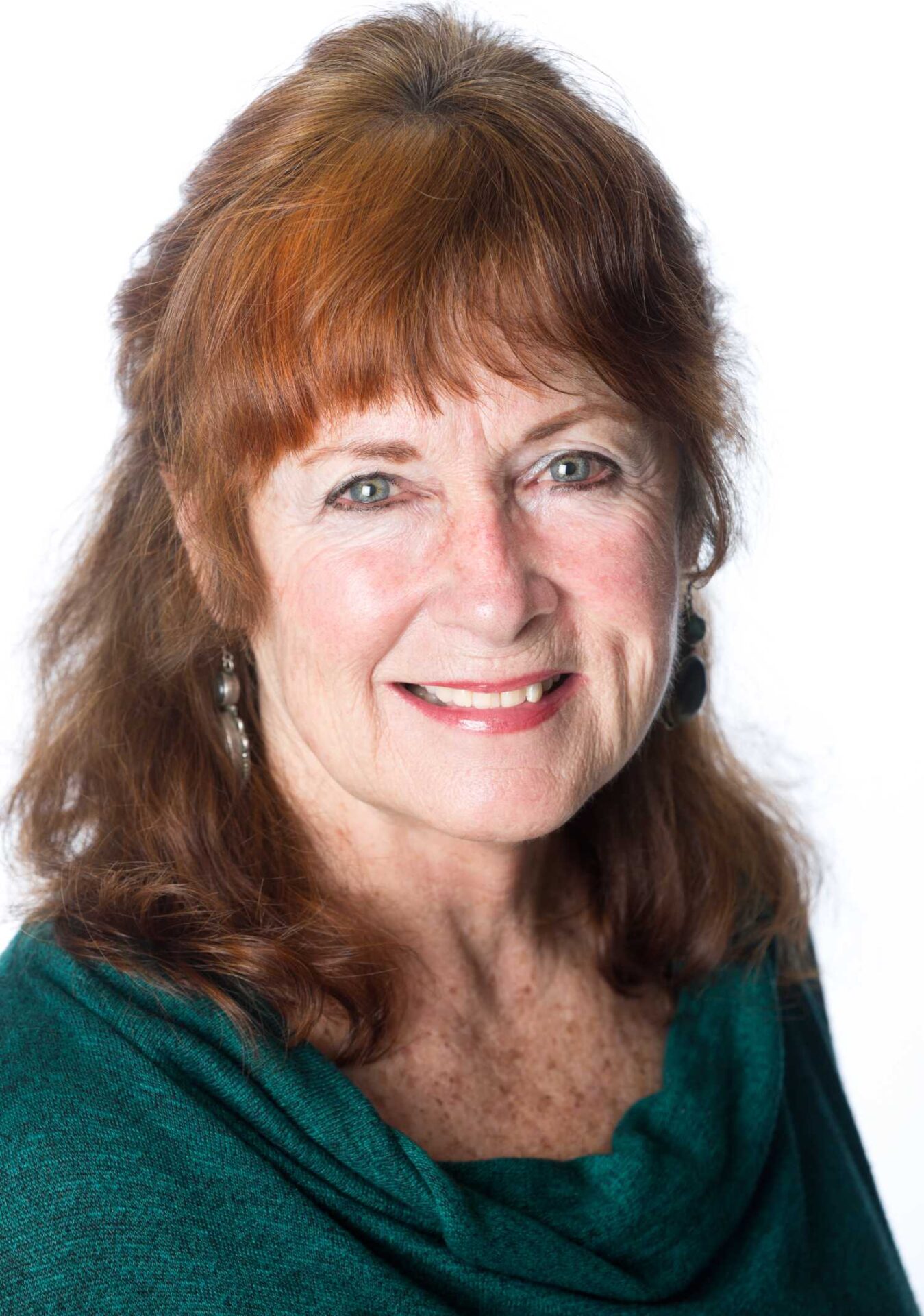 A woman with red hair and green shirt smiling.