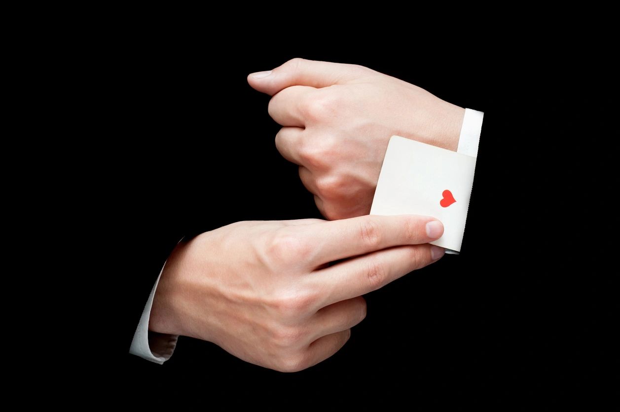 A person holding an ace of hearts card in their hands.